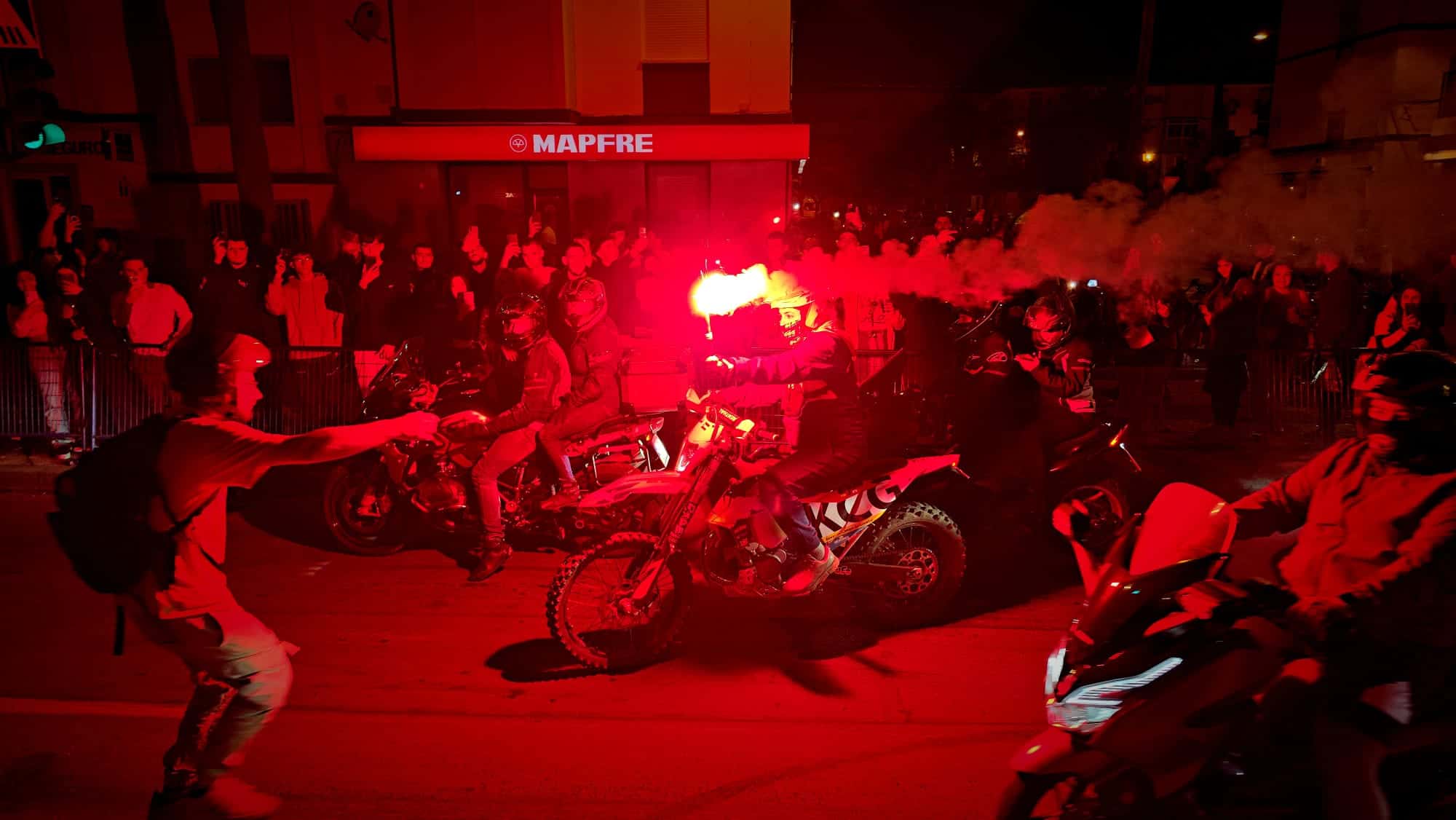 Ambiente nocturno de la auténtica fiesta motera Jerez con motoristas, humo y bengalas rojas.
