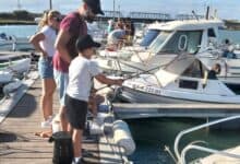 Niños y adultos pescando en el puerto de San Fernando.